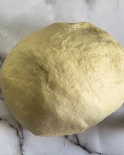 Una palla di pasta è appoggiata su una superficie di marmo.