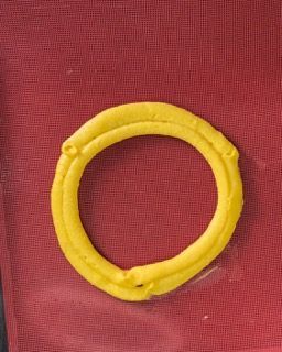 Un anello giallo è appoggiato su un panno rosso.
