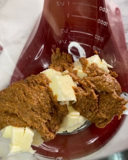 Un becher rosso riempito con una sostanza marrone e burro