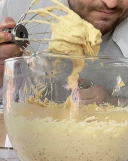 Un uomo sta mescolando un impasto in una ciotola con una frusta.