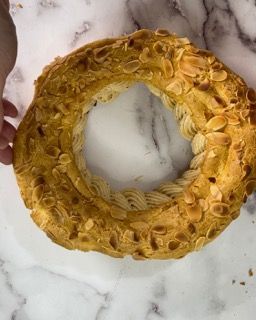 Una persona tiene in mano una ciambella con sopra delle mandorle.