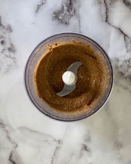 Un robot da cucina riempito con una sostanza marrone su una superficie di marmo.