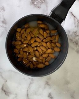 Una pentola piena di mandorle e acqua su un tavolo.