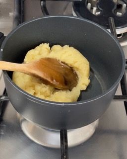Una pentola di purè di patate con un cucchiaio di legno dentro
