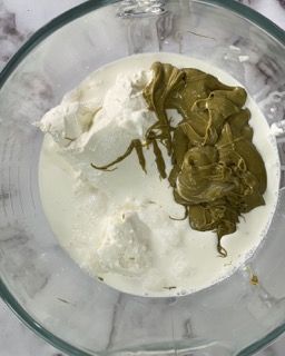 Primo piano di un frullatore riempito con un liquido verde e un liquido bianco.