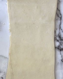 Un pezzo di pasta è appoggiato su un bancone di marmo.