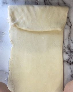 Un pezzo di pasta è appoggiato su un bancone di marmo.