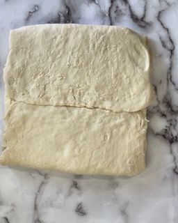 Un pezzo di pasta è appoggiato su una superficie di marmo.