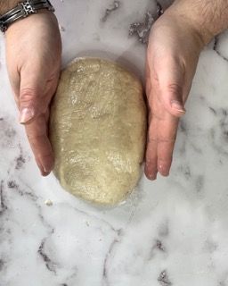 Una persona tiene in mano una palla di pasta.