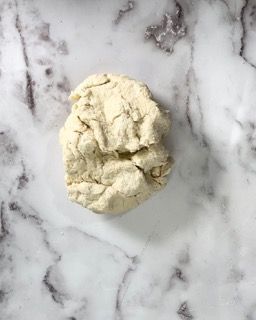 Una palla di pasta è appoggiata su una superficie di marmo.