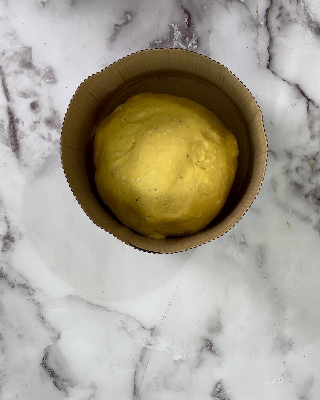 Una palla di pasta è in un bicchiere di cartone su una superficie di marmo.