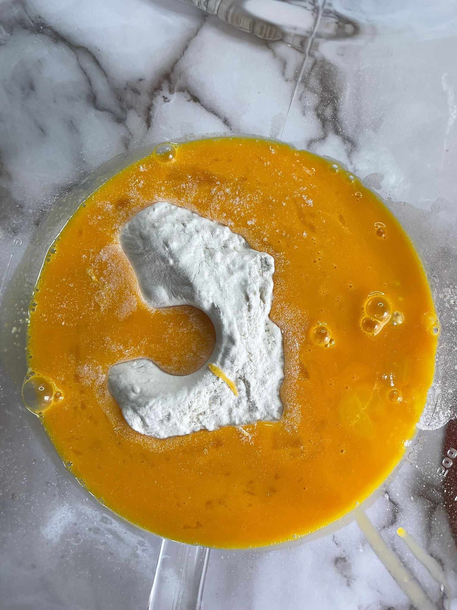 Una ciotola con uova e farina su un tavolo.