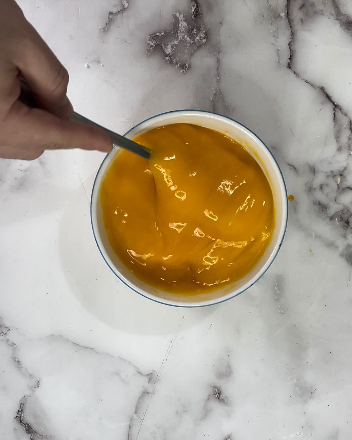 Una persona sta mescolando una ciotola di zuppa con un cucchiaio