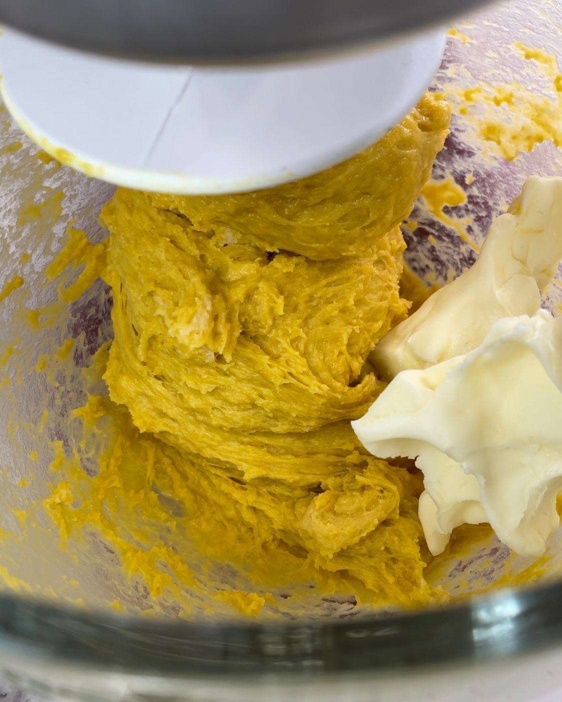 Primo piano di un frullatore pieno di pastella gialla e burro.