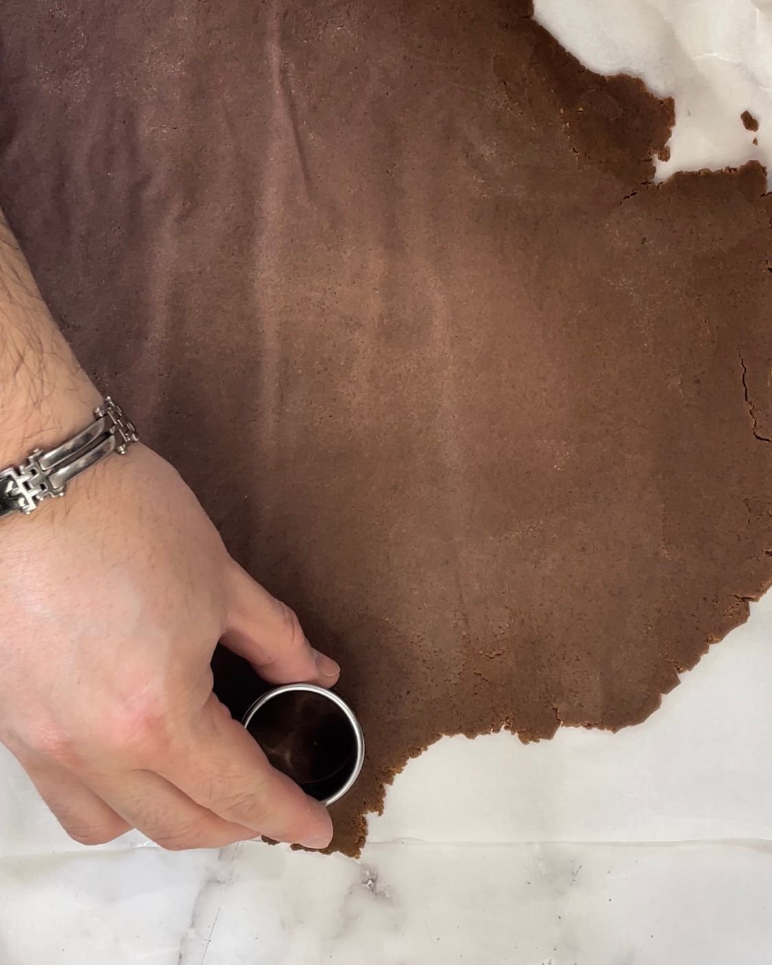 Una persona sta usando uno stampino per biscotti per tagliare un pezzo di pasta al cioccolato.