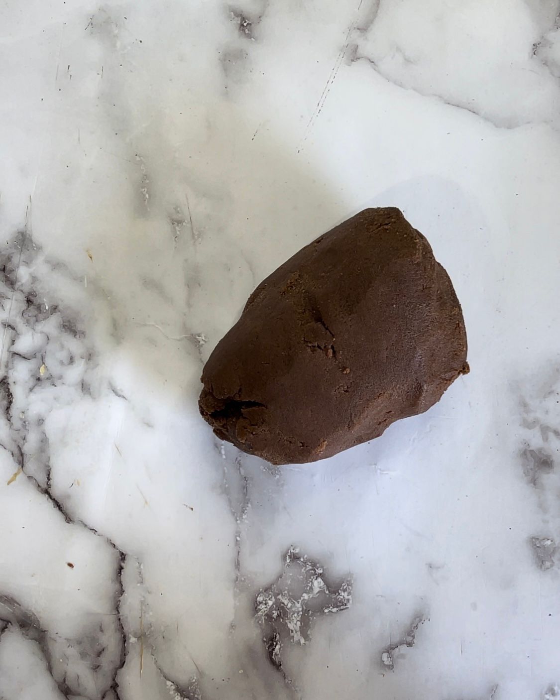 Un pezzo di pasta al cioccolato è appoggiato su una superficie di marmo.