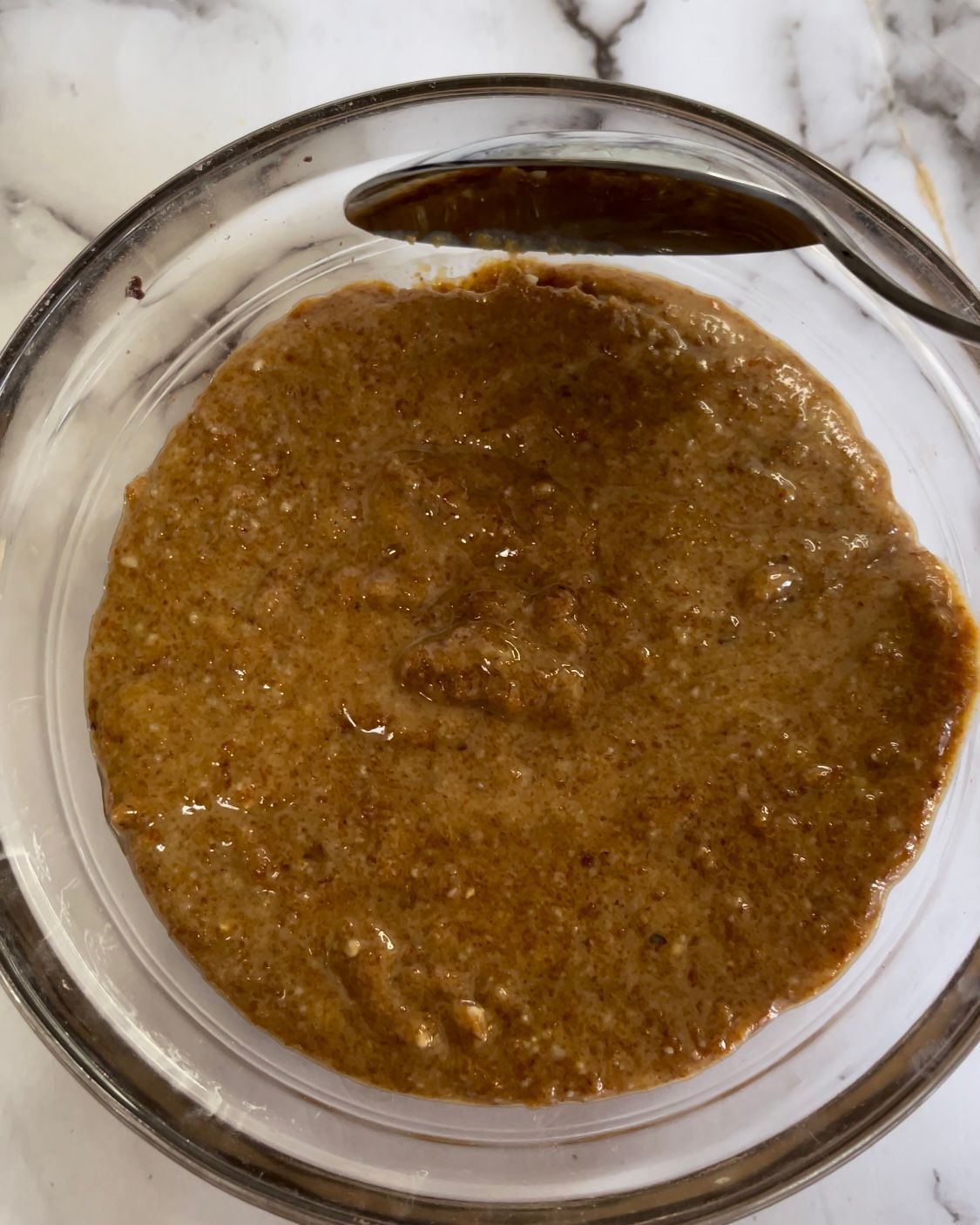 Una ciotola di salsa marrone con un cucchiaio dentro