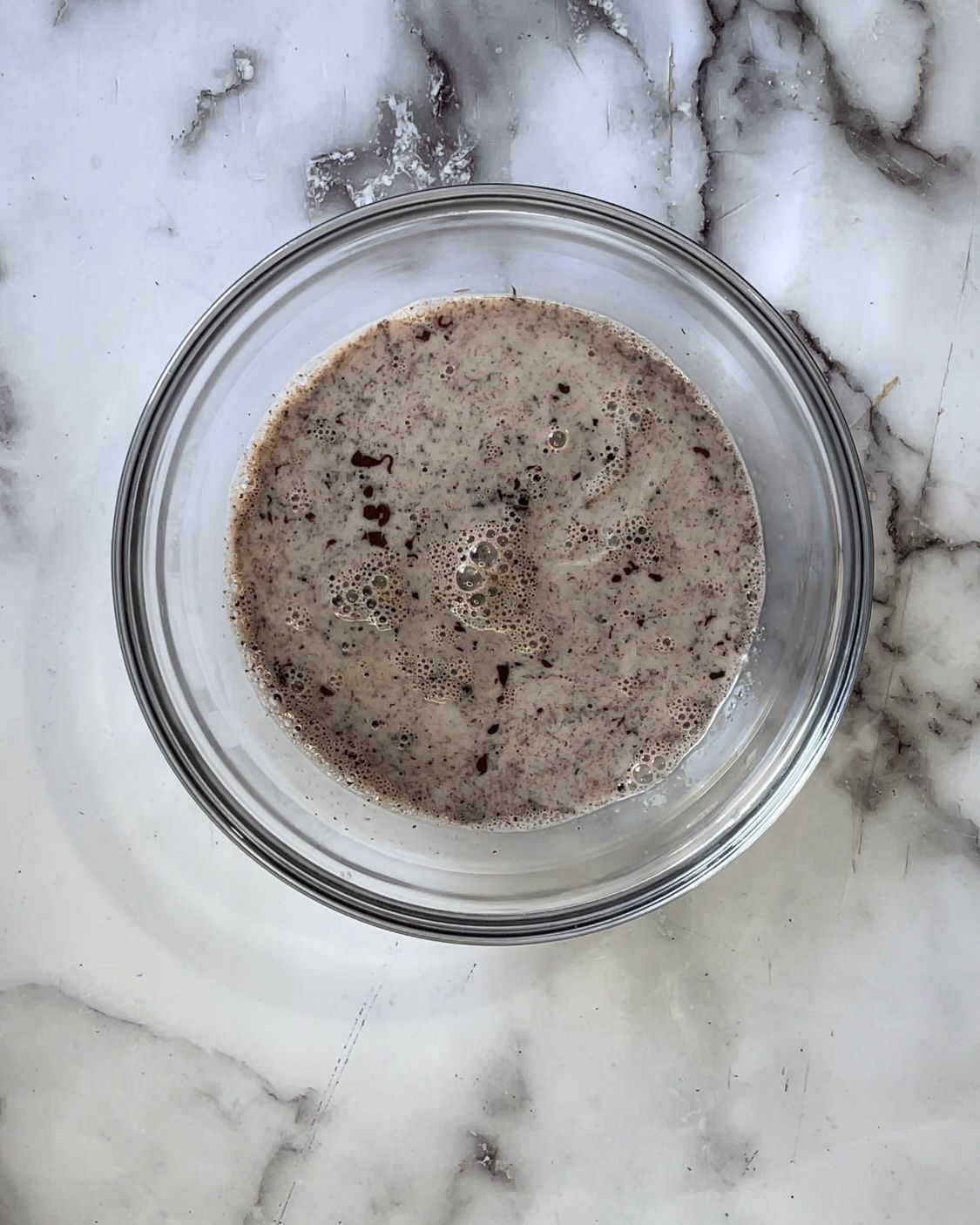 Una ciotola di vetro piena di un liquido marrone su una superficie di marmo