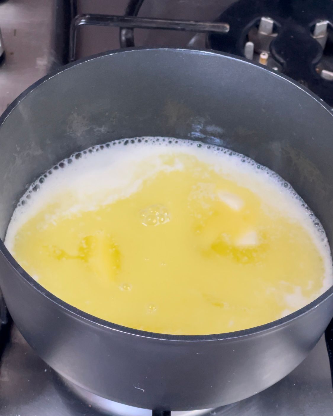Una pentola piena di liquido giallo sta cuocendo sul fornello.