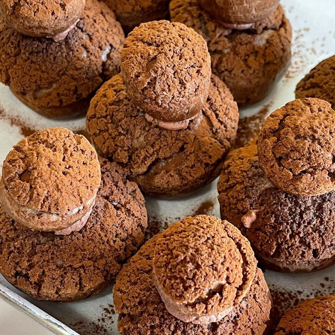 Primo piano di un vassoio di bignè al cioccolato su un tavolo.