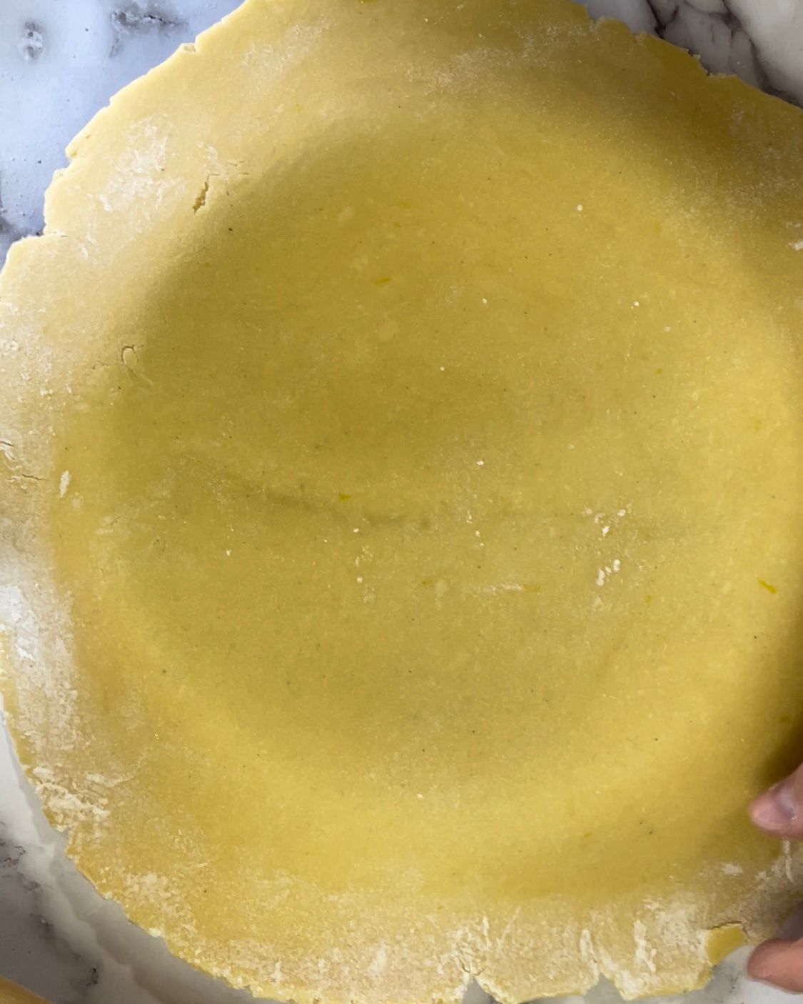 Una persona tiene in mano un pezzo di pasta per torta.