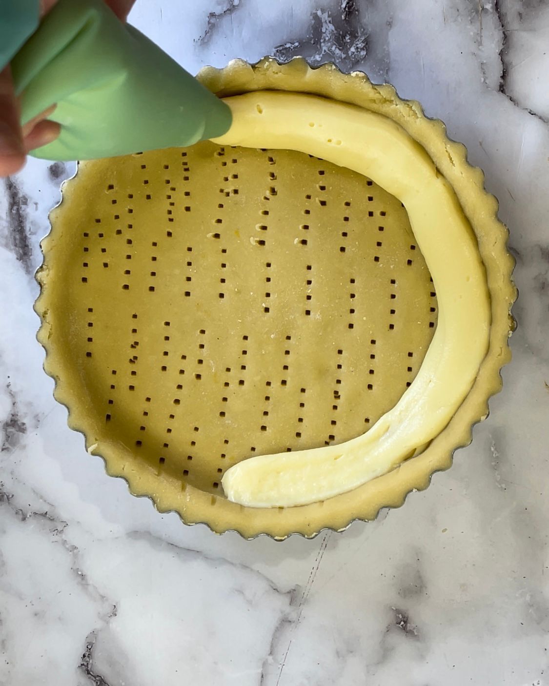 Una persona sta versando la crema nella pasta di una torta.