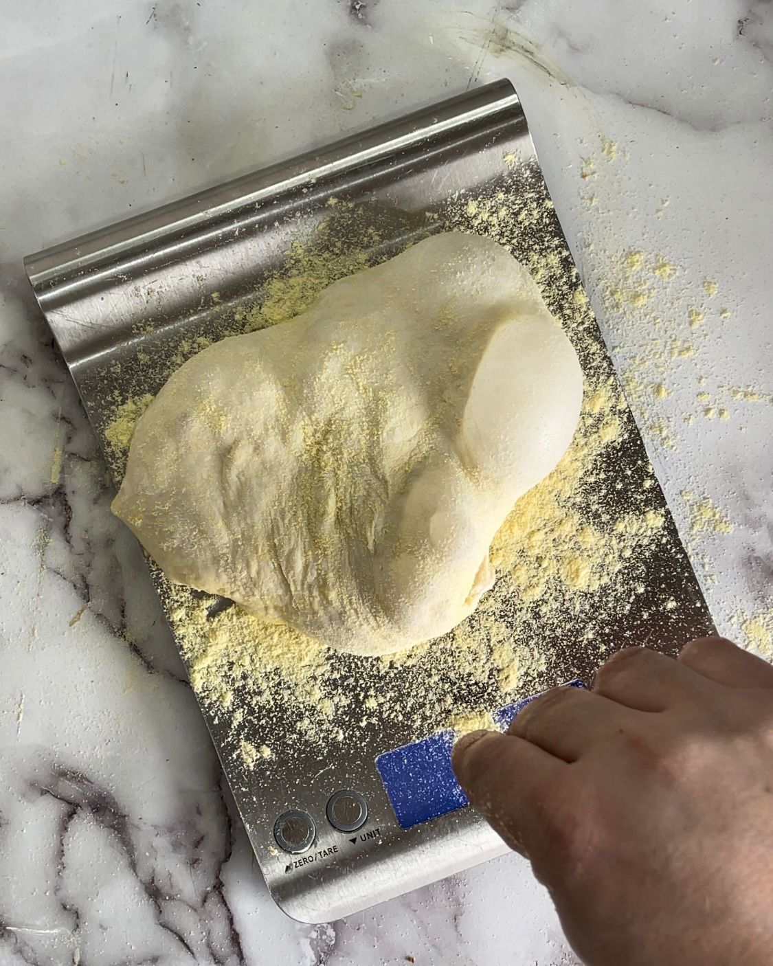 Una persona sta usando una spatola per stendere l'impasto su una teglia.