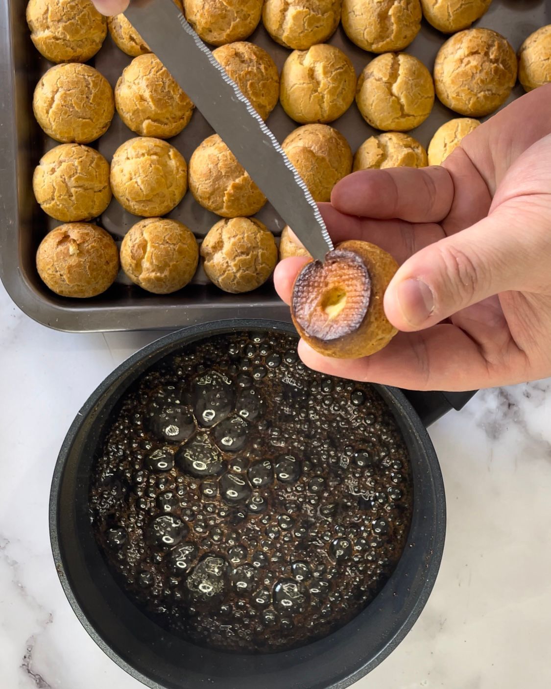 Una persona tiene in mano un biscotto accanto a una pentola di salsa.