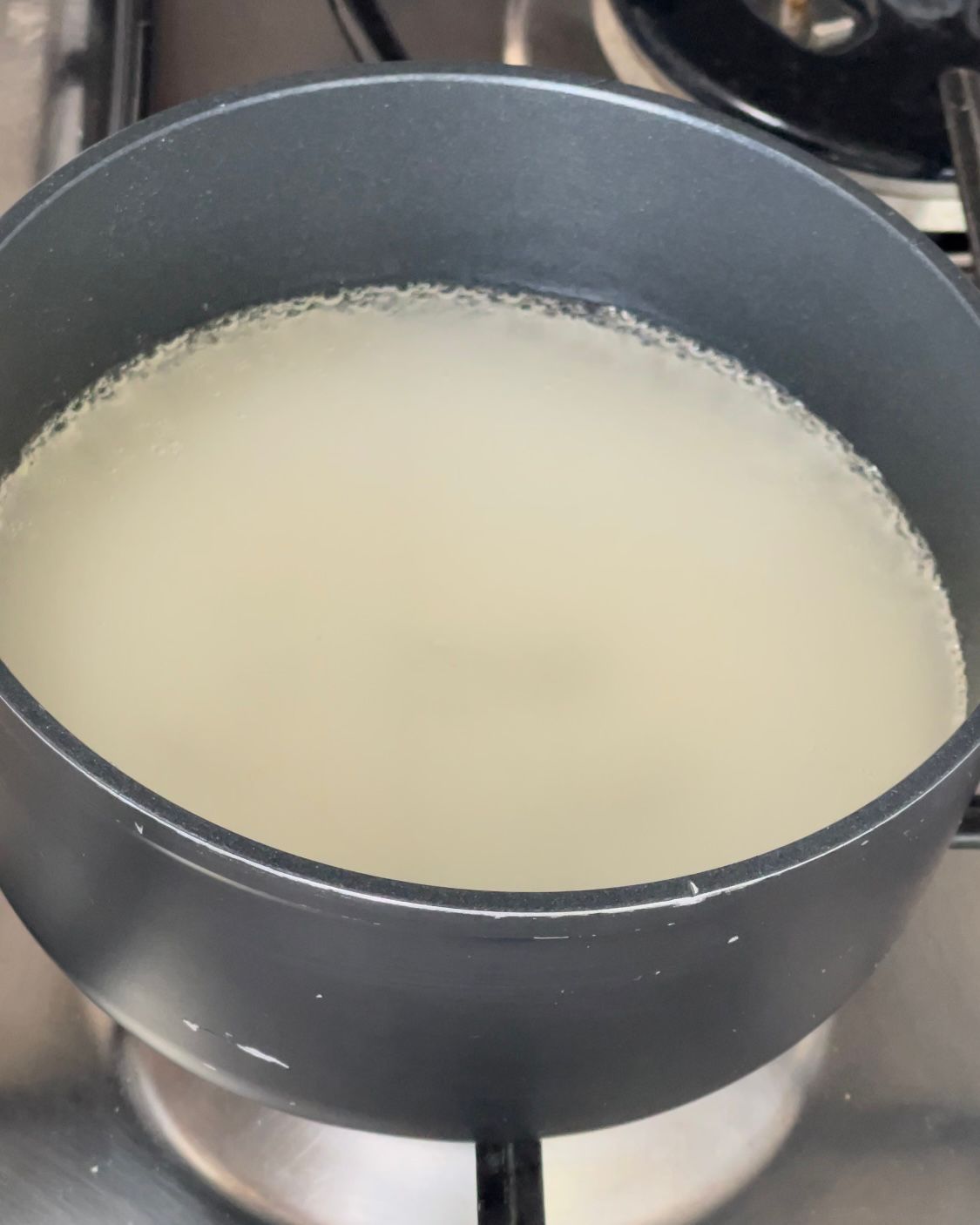 Una pentola piena di liquido è posta sopra un fornello.