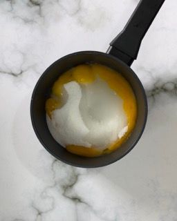 Una padella piena di uova e panna acida su una superficie di marmo.