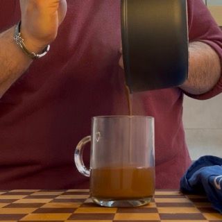 Un uomo sta versando una tazza di caffè da una caffettiera