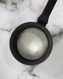 Una tazza di zucchero è appoggiata su una superficie di marmo.