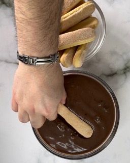 Una persona sta immergendo un biscotto in una ciotola di salsa al cioccolato.