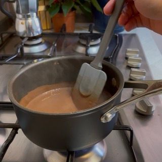 Una persona sta mescolando una pentola di salsa al cioccolato con una spatola
