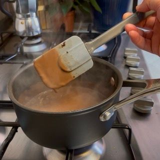 Una persona tiene una spatola sopra una pentola di liquido