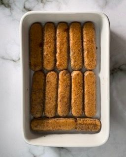 Una teglia bianca piena di grissini su un tavolo.