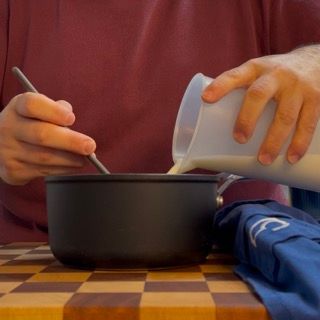 Una persona che versa il latte in una ciotola con un cucchiaio