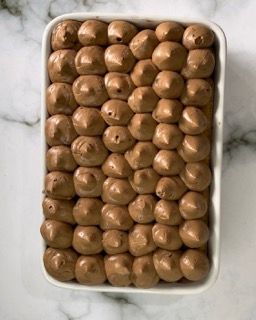 Un contenitore bianco pieno di palline di cioccolato su un tavolo.