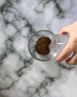 Una persona versa il caffè in un bicchiere su un tavolo.