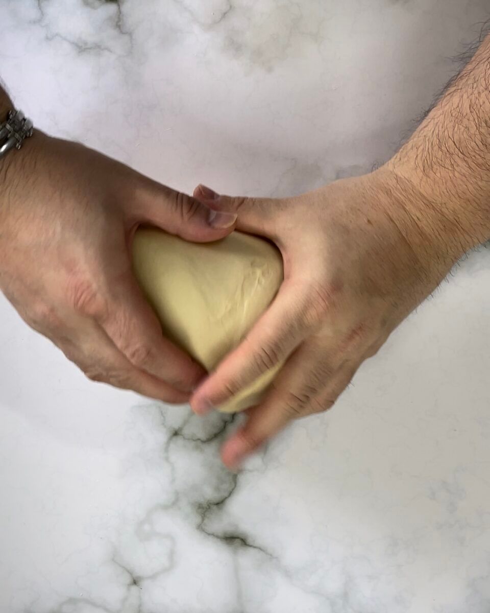 Una persona tiene in mano una palla di pasta.