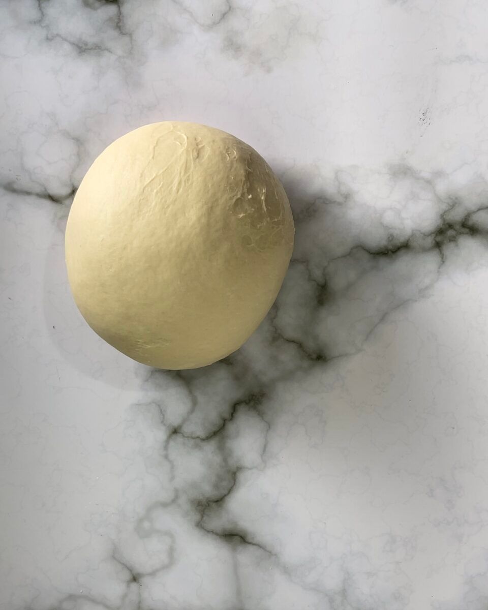 Una palla di pasta è appoggiata su una superficie di marmo.