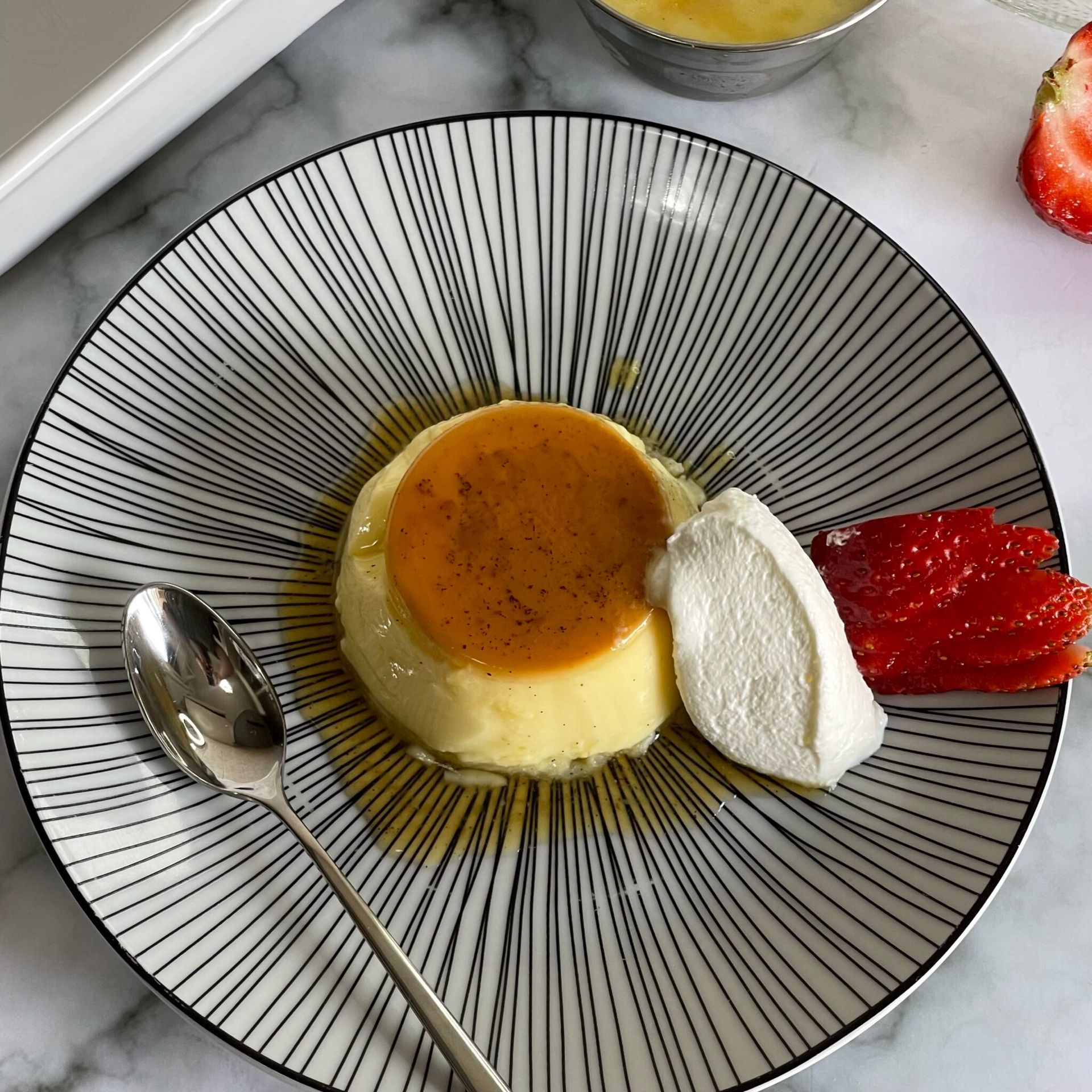 Un piatto di dessert con panna montata e fragole su un tavolo.