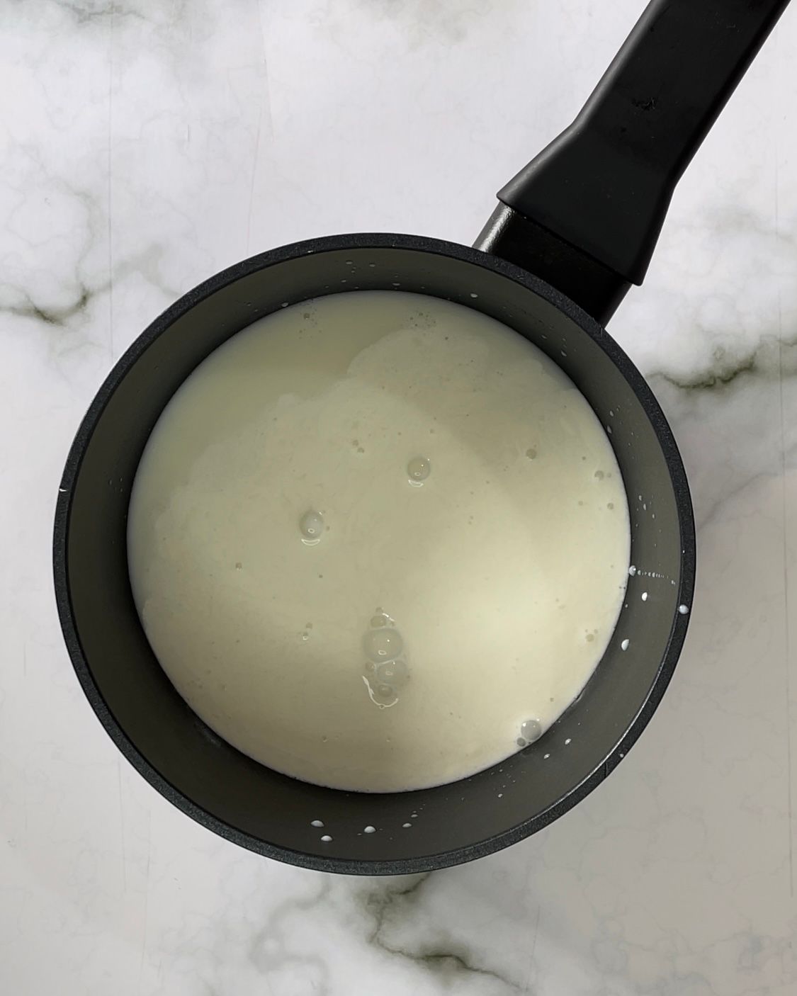 Su un tavolo c'è una pentola piena di liquido bianco.