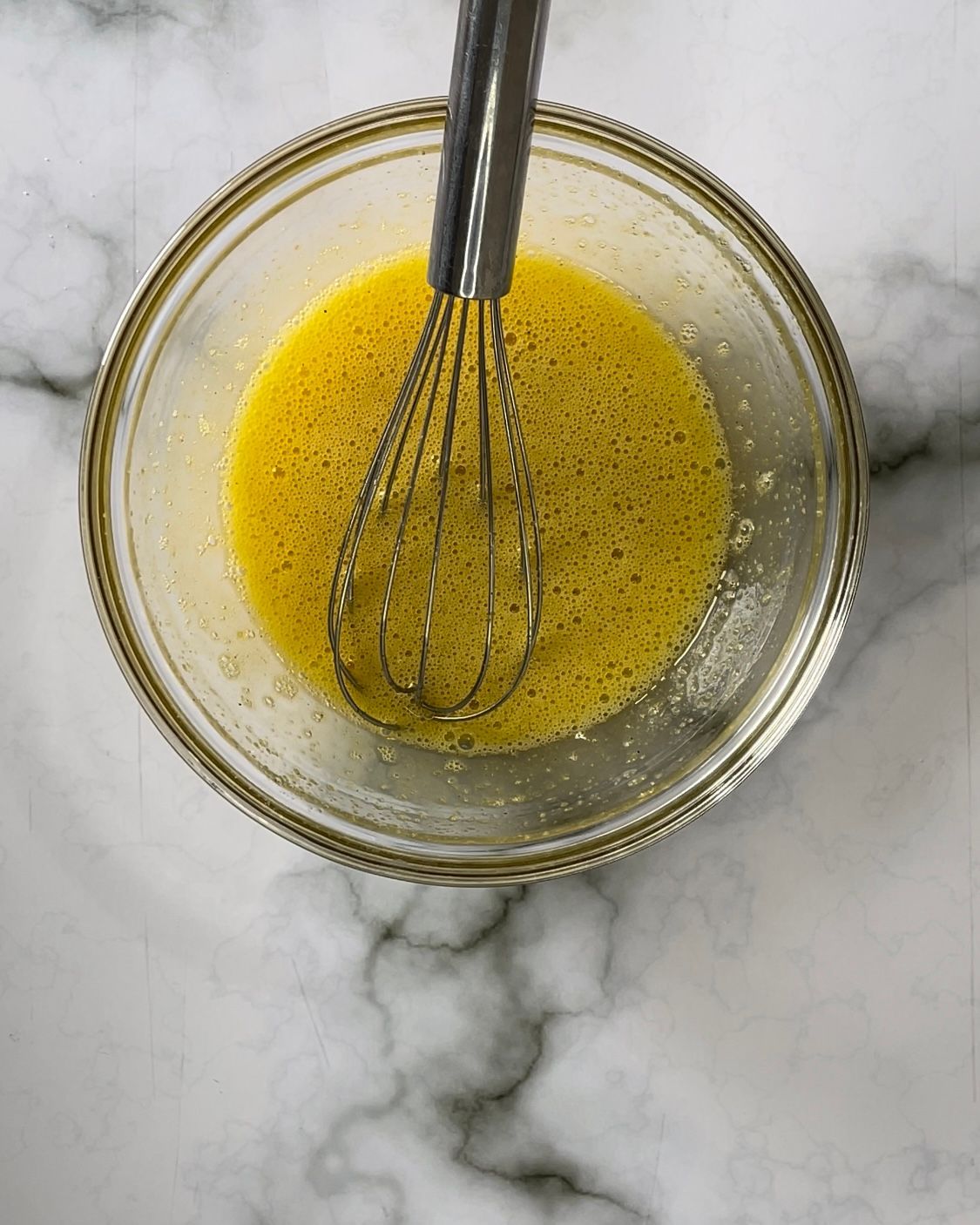 Una frusta è in una ciotola di liquido giallo.