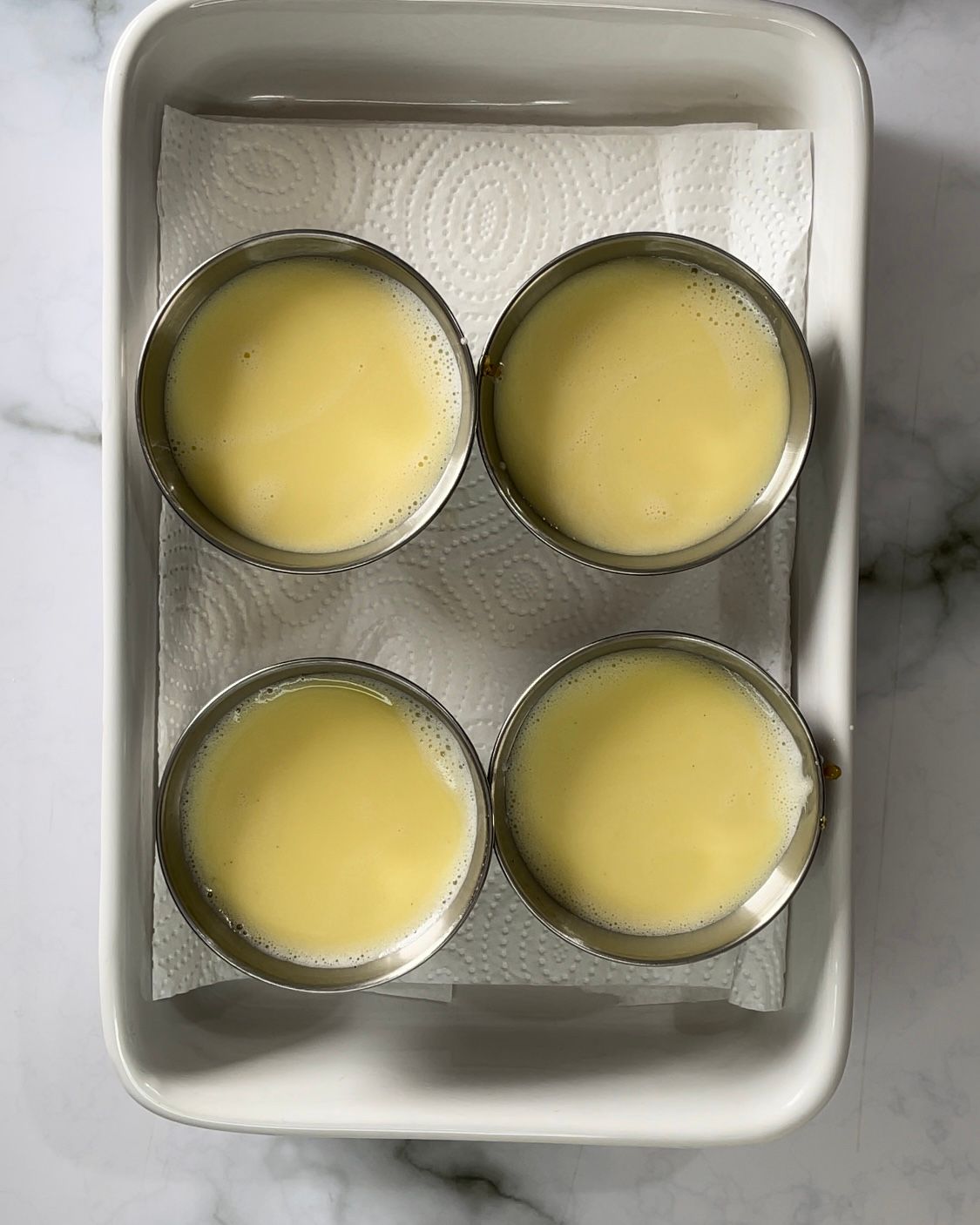 Quattro cupcake sono appoggiati su una teglia bianca e appoggiati su un tovagliolo di carta.