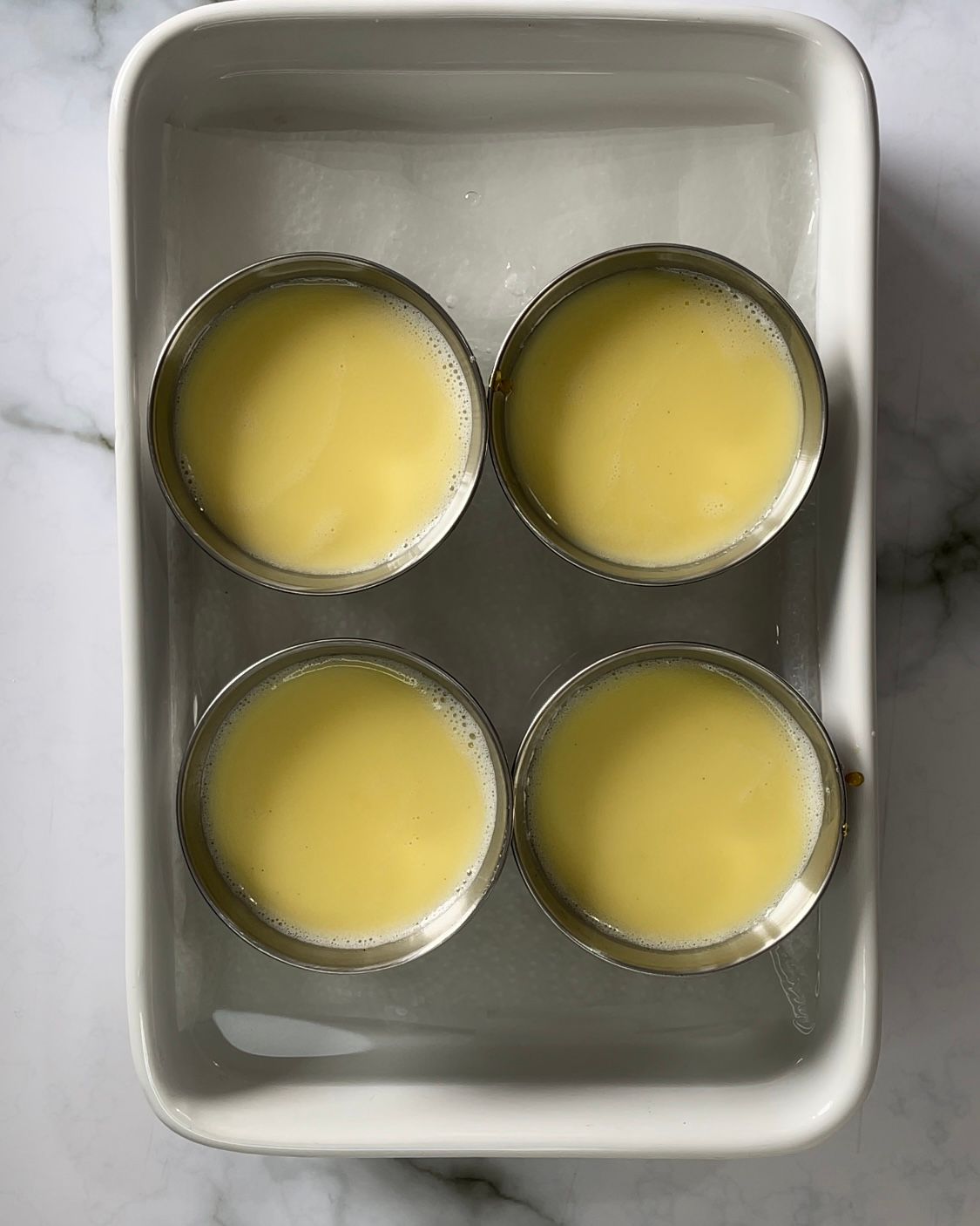 Una pentola bianca riempita con quattro tazze di liquido giallo.