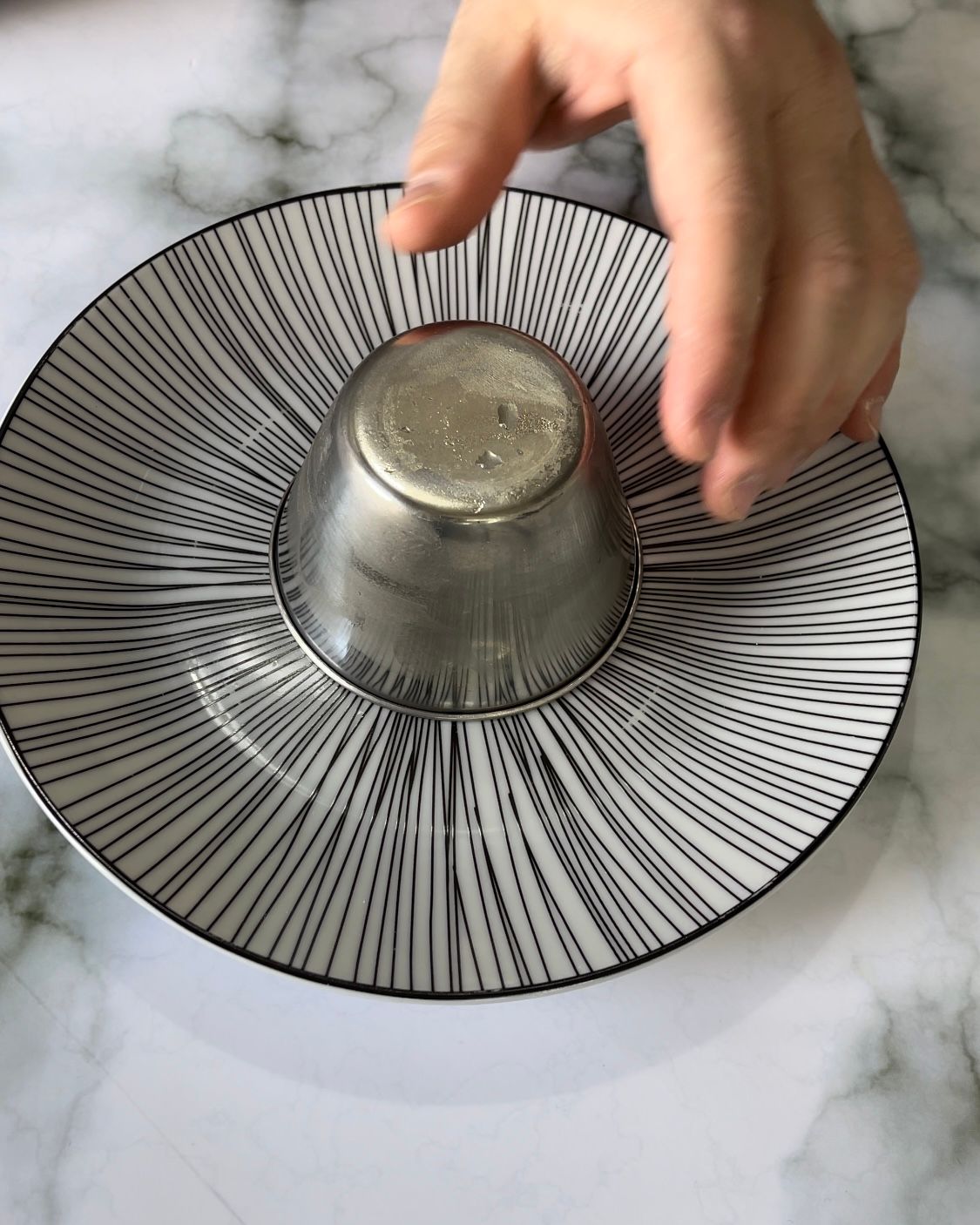 Una persona tiene una tazza sopra un piatto.