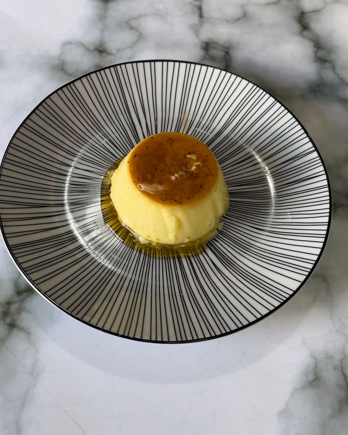 Un piccolo dessert su un piatto bianco e nero su un tavolo.