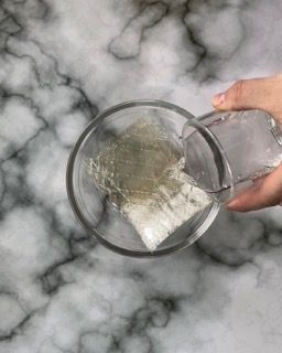 Una persona sta versando qualcosa in un bicchiere su un tavolo.