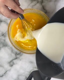 Una persona sta versando il latte in una ciotola di salsa all'arancia.